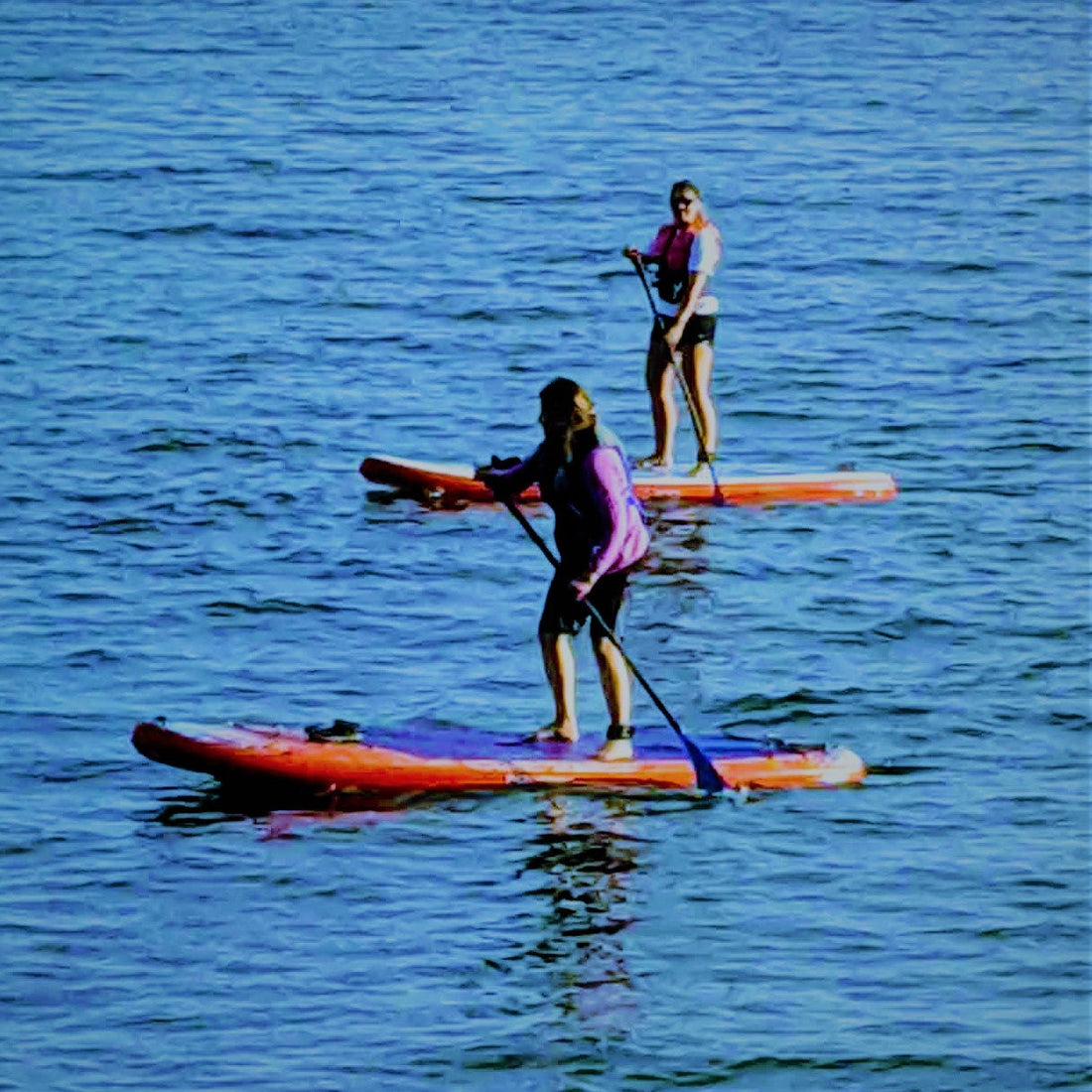 Two beginner Paddle boarders out on the ocean on a nice day.