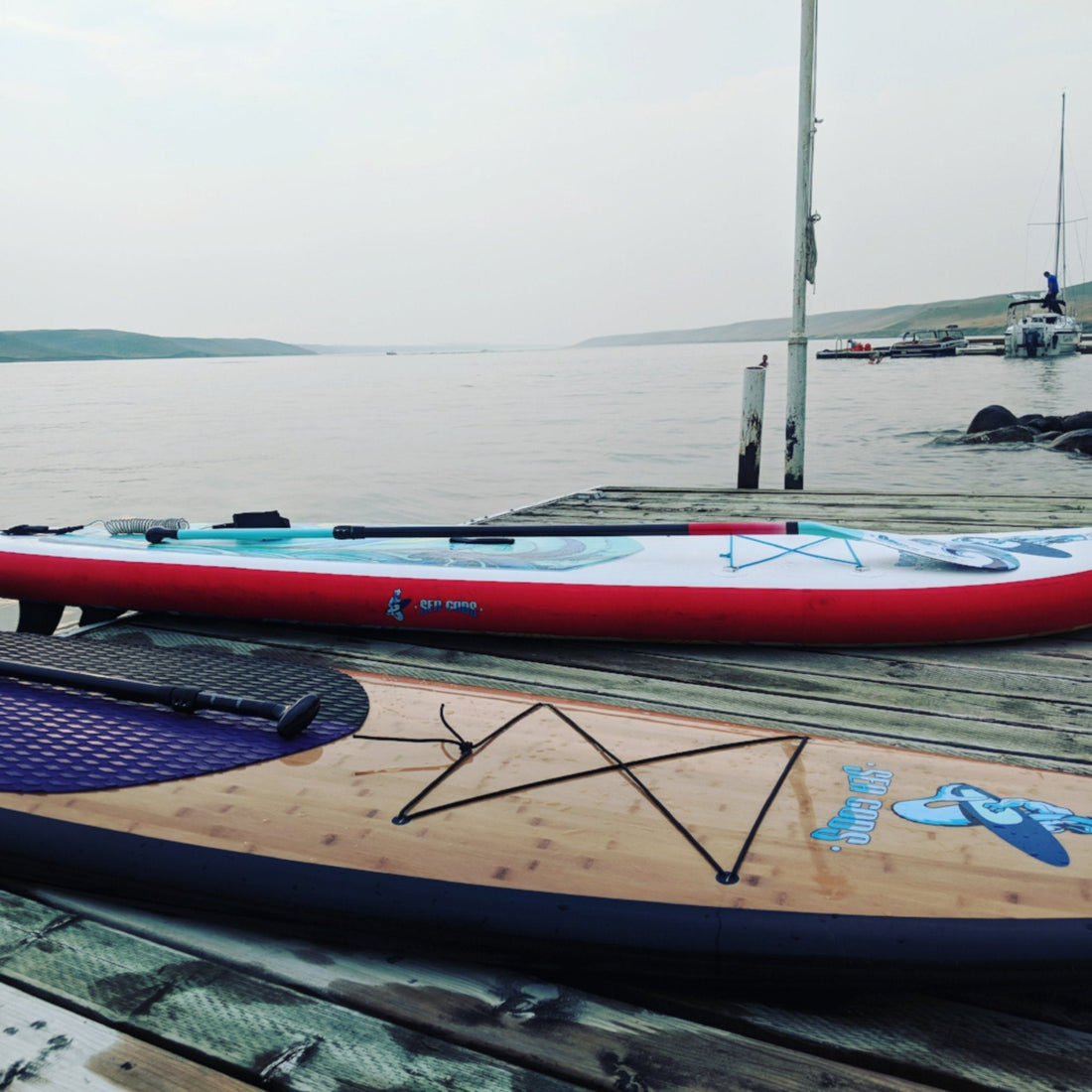 Composite paddle board and inflatable paddleboard on dock at lake